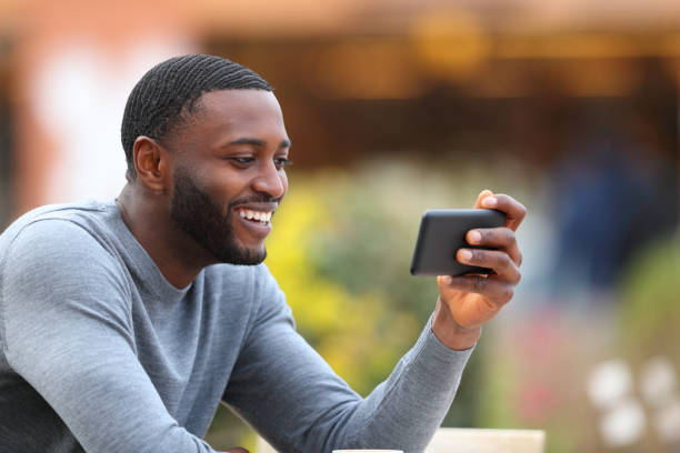 Man with black skin watching media on smart phone in a bar